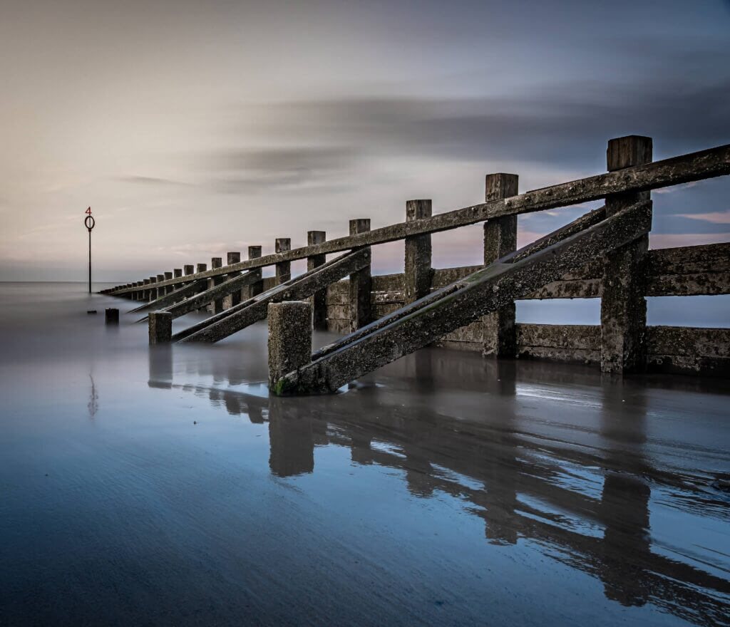 A wooden jetty reaching into still water, photographed by David Barco