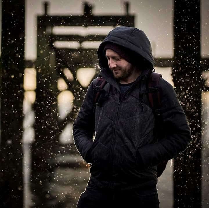 A hooded figure in a dark doorway, a portrait by David Barco