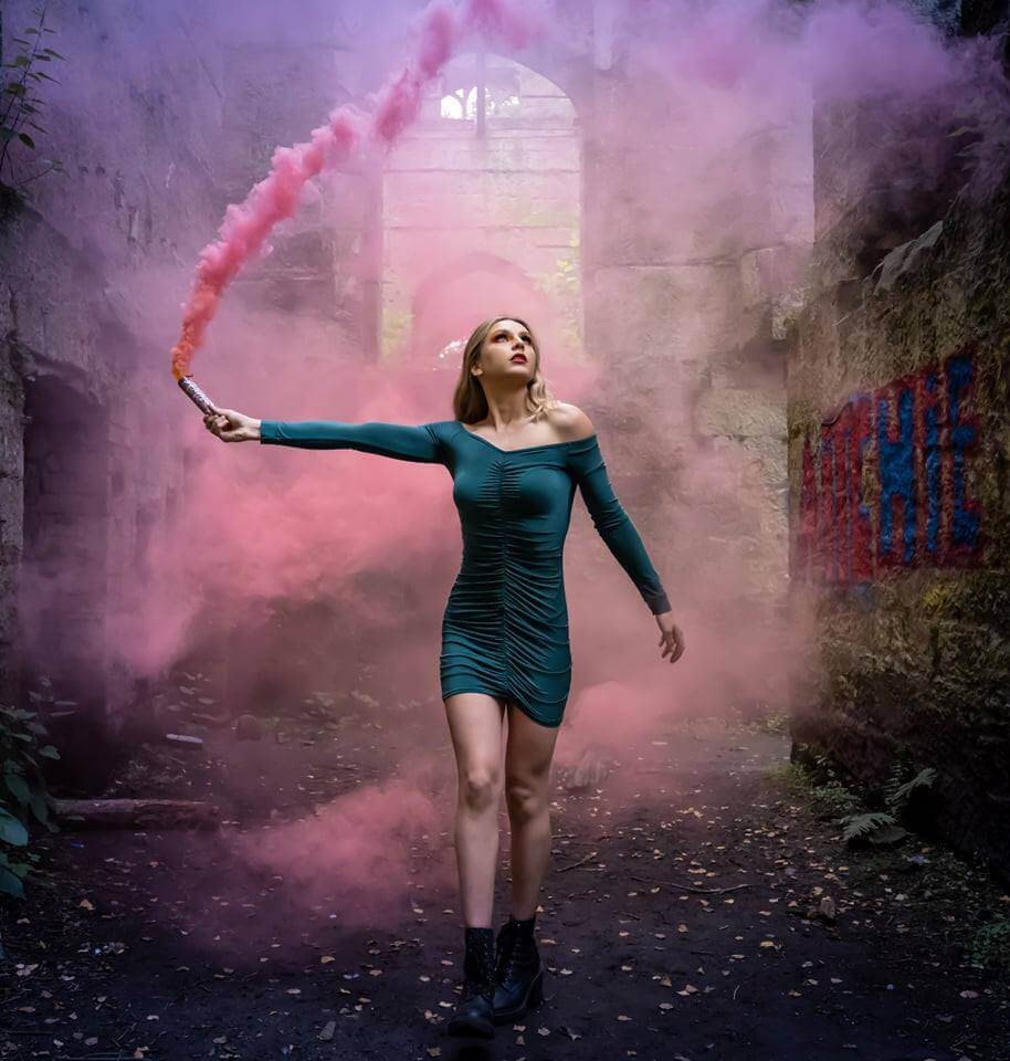 A woman with pink smoke in a woodland, a portrait by David Barco