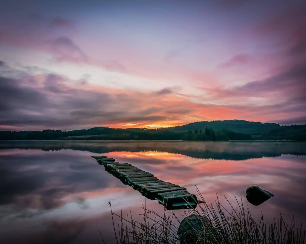A loch at sunset under pink clouds, photographed by David Barco