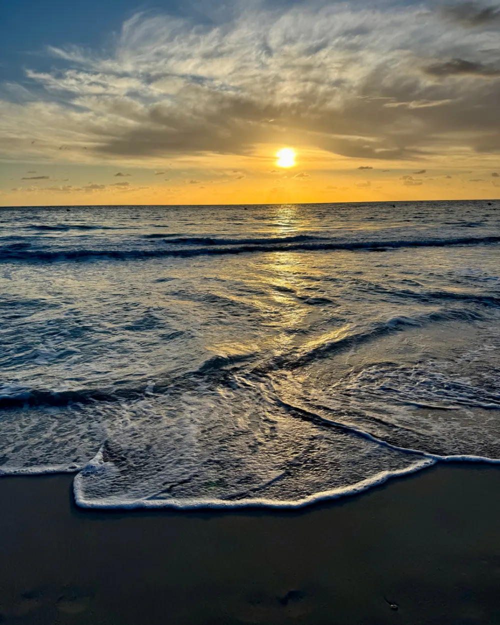 The sun rising over the sea at Cala Millor, Mallorca, with a wave washing up the sand