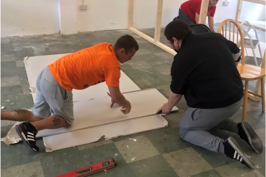 Two people fitting new flooring in a Yellow Ribbon house